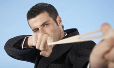 a man in a suit holding two chopsticks