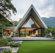 a triangular shaped house in the middle of a lush green field