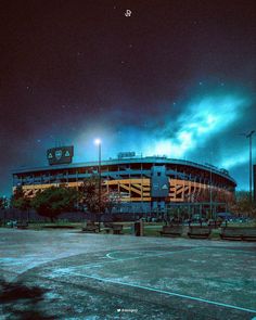 an empty baseball stadium at night with the lights on and clouds in the sky above