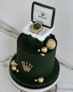 a green cake with gold decorations and a rolex watch on top