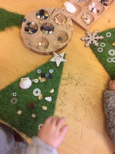 two children are making christmas trees out of buttons and fake grass on a table with other items