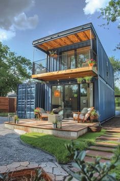 a house made out of shipping containers in the grass with stairs leading up to it