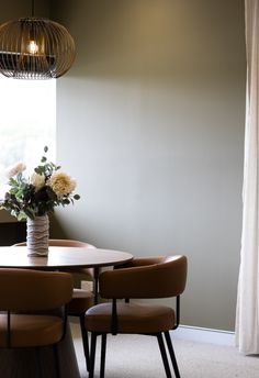 a dining room table with chairs and a vase filled with flowers on top of it