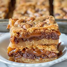 a stack of dessert bars sitting on top of a white plate next to a pan