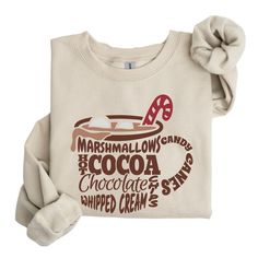 Marshmallows Hot Cocoa Hot Chocolate Chips Whipped Cream Candy Cans Sweatshirt, Cute Christmas Shirt, Trendy Christmas Tee,Coffee Lover Gift ---------- Ordering Your Custom Design T-shirt: Step by Step ---------- 1. Select your preferred t-shirt color. 2. Specify your desired size. 3. Pick the color for both your design and text. 4. Ensure that each step of your order is accurately completed. M A T E R I A L S → Our solid color options such as White and Black consist of 100% Cotton. → The Heathered Colors are a blend of cotton and polyester, ensuring a luxuriously soft feel. → Crafted as Short Sleeve Crew-Neck Unisex T-Shirts. → Composed of soft, high-quality Sueded Jersey fabric. → Pre-shrunk for lasting fit. → Taped shoulder-to-shoulder for enhanced durability. → Tear away label for adde Hot Cocoa Shirt, Cocoa Hot Chocolate, Chocolate Whipped Cream, Cute Christmas Shirt, Cream Candy, Cocoa Chocolate, Cute Christmas Shirts, Coffee Lover Gift, Sweatshirt Cute