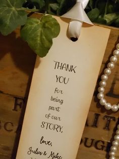 a thank note attached to a wooden box with pearls and a plant in the background