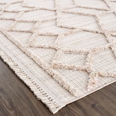 a white rug on top of a wooden floor with a wood flooring area in the background