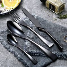 three forks and two spoons sitting on top of a cloth next to a plate