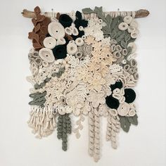 a crocheted wall hanging with flowers and leaves