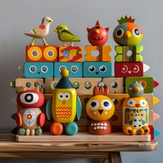 an assortment of colorful wooden toys sitting on top of a wood table in front of a gray wall