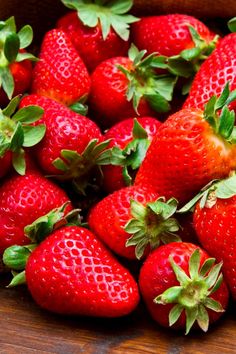 a bunch of strawberries sitting on top of a wooden table