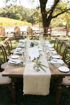 an outdoor table set with place settings and place cards for guests to sit down at