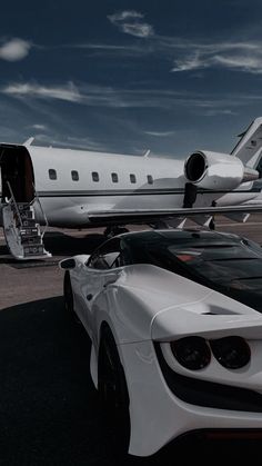 a white sports car parked in front of an airplane