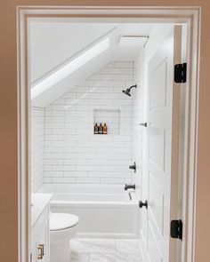 an open door leading to a bathroom with a white toilet and bathtub in it