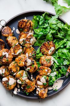 grilled shrimp and spinach salad on a black plate with a fork in it