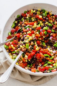 a white bowl filled with black beans, corn and veggies next to a spoon