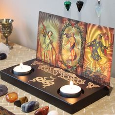 two candles sitting on top of a table next to some rocks and glass vases