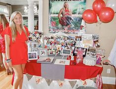 a woman standing in front of a table with pictures and balloons