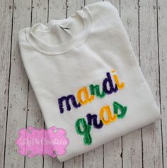 Looking for a new trendy shirt to wear this Mardi Gras? The lettering is embroidered onto a heavy weight unisex Gildan tee or Gildan Sweatshirt with a commercial embroidery machine. *Washing instructions-please wash and dry fringe shirt inside a delicate garment bag to guarantee the longevity of the item. Each time the shirt is washed the fringe becomes more fluffy. All items are custom made here at Lilly Pie Creations White Machine Embroidered Tops For Streetwear, Embroidered Text T-shirt For College In Fall, Multicolor Embroidered Logo Tops For Fall, Fall Tops With Multicolor Embroidery And Logo, Fall Multicolor Embroidered Logo Tops, Long Sleeve Embroidered T-shirt For College, Crew T-shirt With Letter Embroidery For College, Crew Neck T-shirt With Letter Embroidery For College, Custom Embroidery Crew T-shirt For College