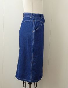 "~ 1970s denim skirt featuring, a high yoked waist lots of white top stitching belt loops on the waistband a pocket at each hip it snaps all the way down the front falls to just below the knee ~ of a mid weight, cotton denim in a dark blue ~ labeled \"Cheryl Tiegs\", (supermodel turned fashionista), this is tagged a size 8, measurements when laid out flat are: 12 1/4 inches at the waist 18 inches at the hip 25 inches from waist to hem ~ would best fit a size small to medium ~ in good, preworn, v Retro Fitted Denim Skirt With Pockets, Retro Fitted Denim Skirt, Vintage High-rise Skirt With Pockets, Vintage Cotton Denim Skirt, Vintage High Rise Fitted Skirt, Vintage Denim Skirt With Pockets, Vintage High Rise Cotton Skirt, Vintage Medium Wash Bottoms For Work, Retro Denim Skirt With Pockets In Medium Wash