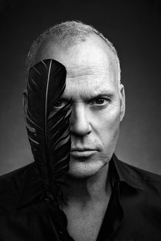 a man with a black feather on his face and an image of a person behind him