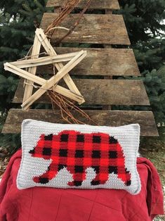 a red and black bear pillow sitting next to a christmas tree