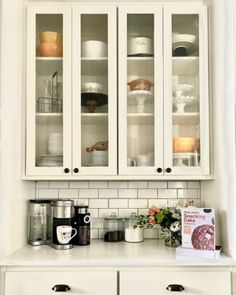 a kitchen with white cabinets and dishes on the counter