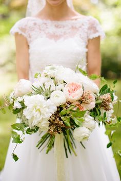 a bride holding a bouquet of white and pink flowers