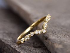 a yellow gold wedding band with white diamonds on the outside, sitting on top of a rock