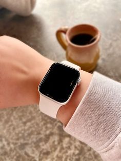 an apple watch on someone's wrist with a cup of coffee in the background