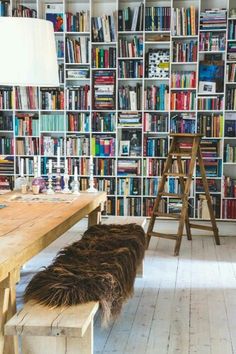 a room filled with lots of books next to a wooden table