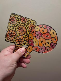 a hand holding up a sticker with an image of flowers in the shape of speech bubbles