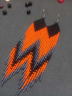 an orange and black beaded necklace with beads on it, next to other beads