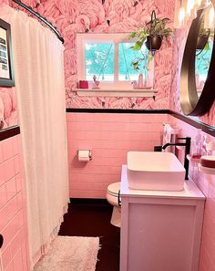 a bathroom with pink walls and flooring has a sink, mirror, toilet and bathtub