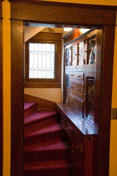 an open door leading to a hallway with red carpeted stairs and stained glass windows