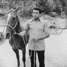 a man standing next to a horse on a dirt road