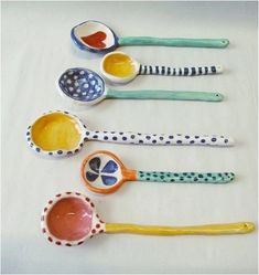 five colorful spoons lined up on top of a white table with polka dot designs