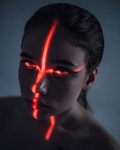 a woman with red light painted on her face and chest, looking at the camera