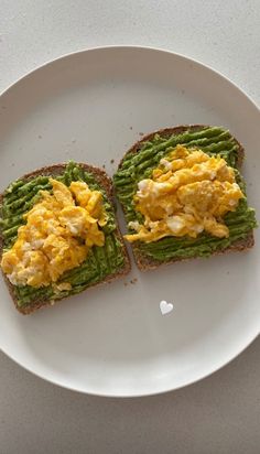 two pieces of toast with eggs and green beans on it sitting on a white plate