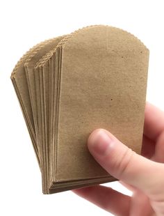 a hand holding a stack of brown paper