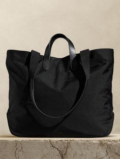 Rugged and minimalist, this canvas and buffalo leather tote bag is designed with space to spare thanks to a large, uninterrupted interior with a snap closure.  We added one zip pocket inside to keep track of small items like phones and keys, as well as two sets of straps so you can carry by hand or on the shoulder.  Snap top closure.  One interior zip pocket.  Buffalo leather straps, Fully lined.  Height: 15. 5" Top width: 20. 5" Bottom width: 15. 75" Depth: 6. 5" Shoulder strap drop: 13. 5" Trendy Purses, Suede Tote, Bag Women Fashion, Nylon Tote Bags, Stylish Handbags, Handbag Heaven, Buffalo Leather, Nylon Tote, Bag Trends