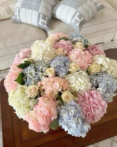 a bouquet of flowers sitting on top of a wooden table next to two pillow cases