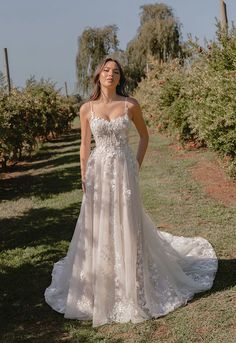 a woman standing in an apple orchard wearing a wedding dress