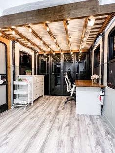 the interior of an rv with wood flooring and white cabinets on either side of it