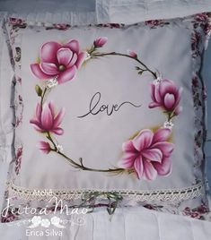 a decorative pillow with pink flowers and the word love written in cursive writing