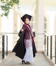 a woman in a graduation gown and hat is walking down the street with her coat on