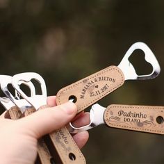 two pairs of personalized wine openers are being held by someone's hand