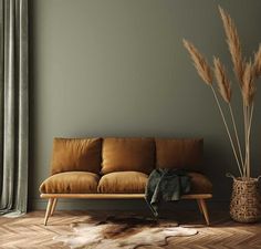 a brown leather couch sitting next to a tall plant on top of a hard wood floor