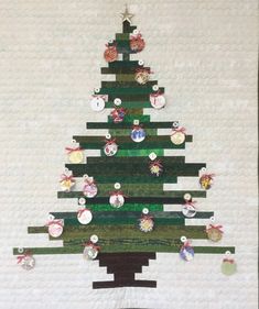 a christmas tree made out of strips of paper and buttons on a quilted wall hanging