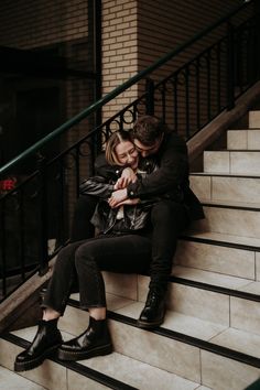 a man and woman are sitting on the stairs hugging each other while looking at each other